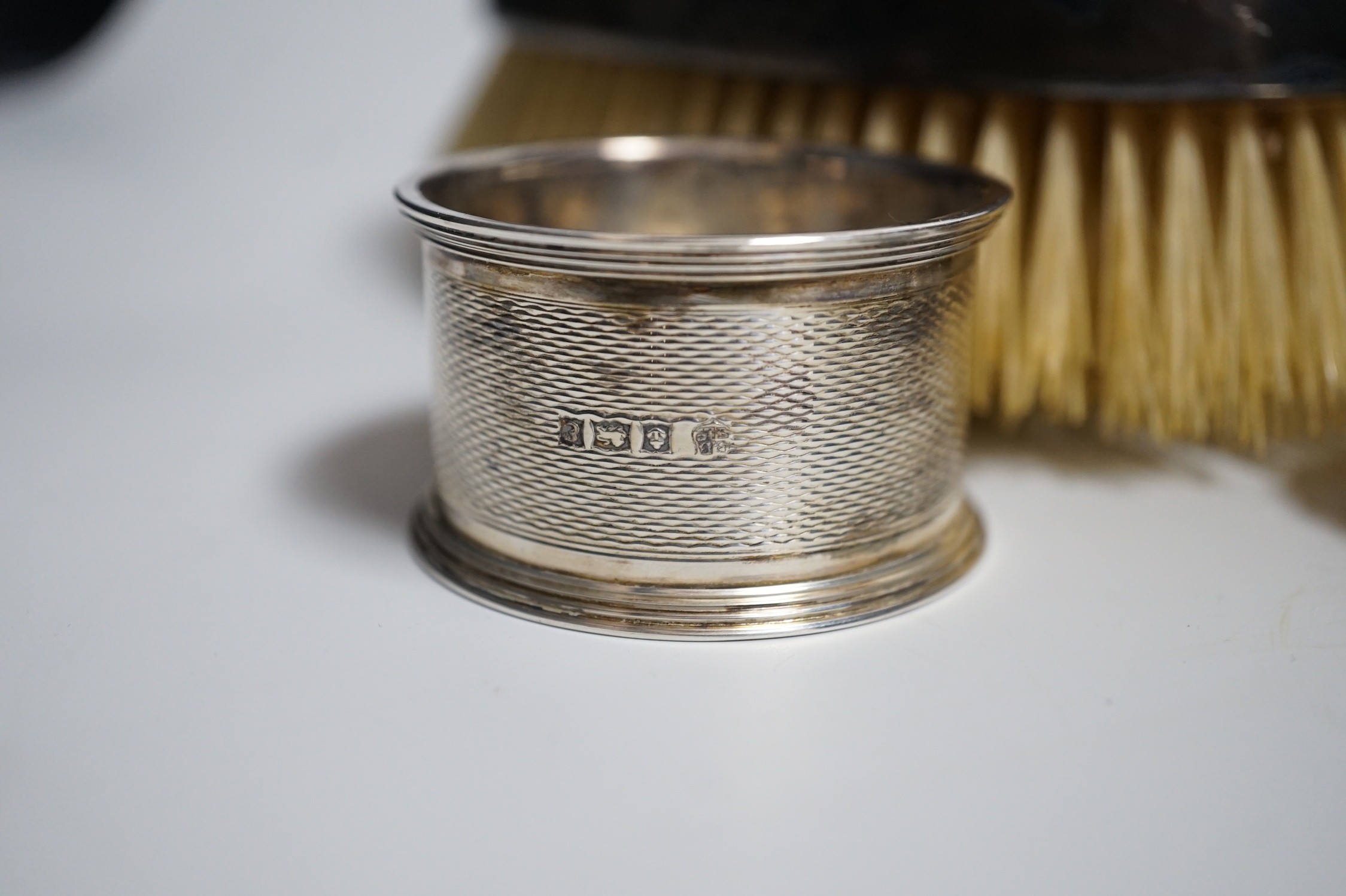 A mixed group of silverware including a pair of silver mounted clothes brushes, two rattles, a napkin ring, a christening trio and mug.